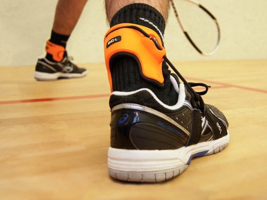 An EXO-L ankle ligament brace worn over a sock and sports shoe on court
