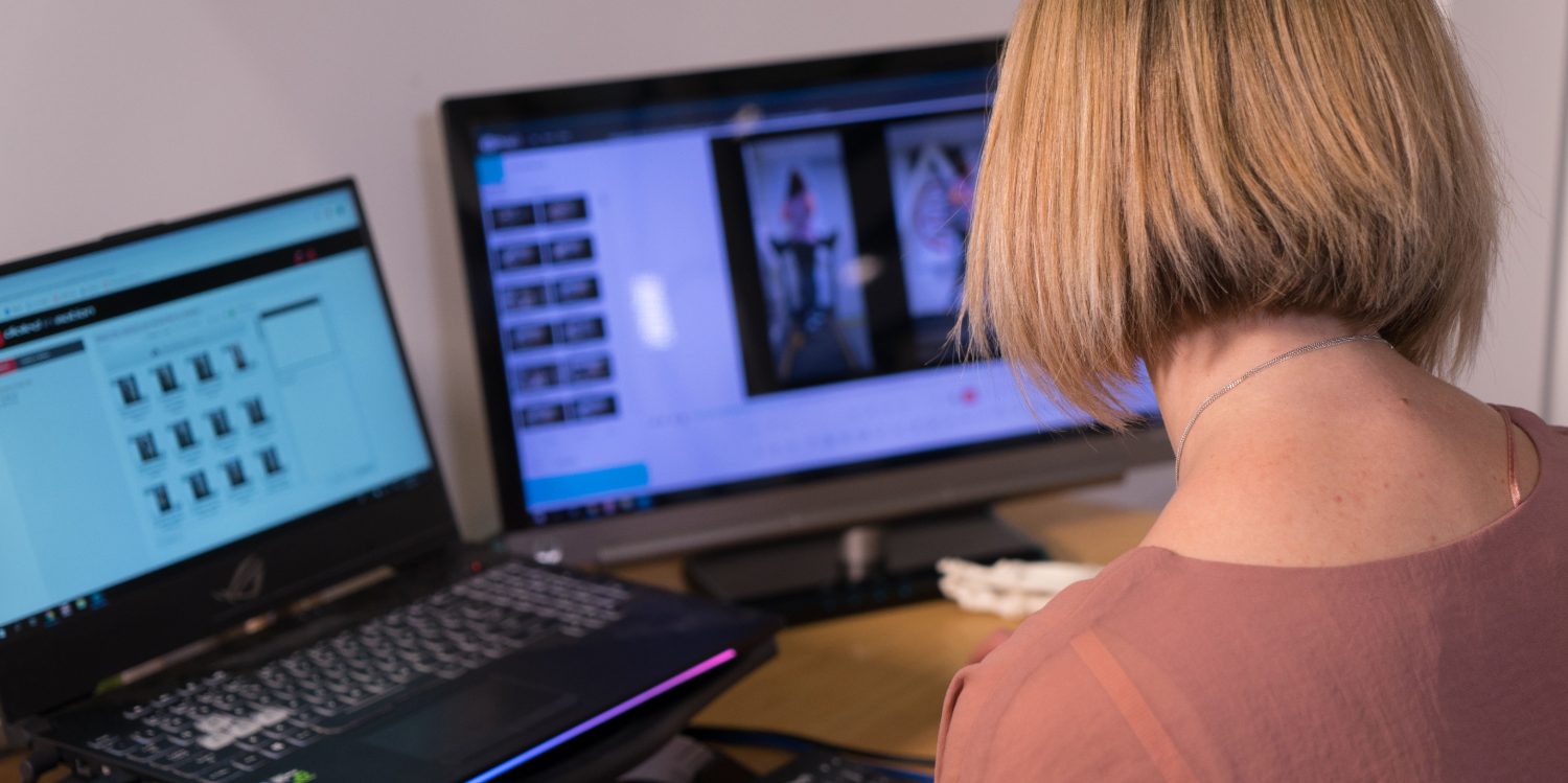 A Capital Podiatry podiatrist reviewing a patient's gait-analysis capture on dual screens