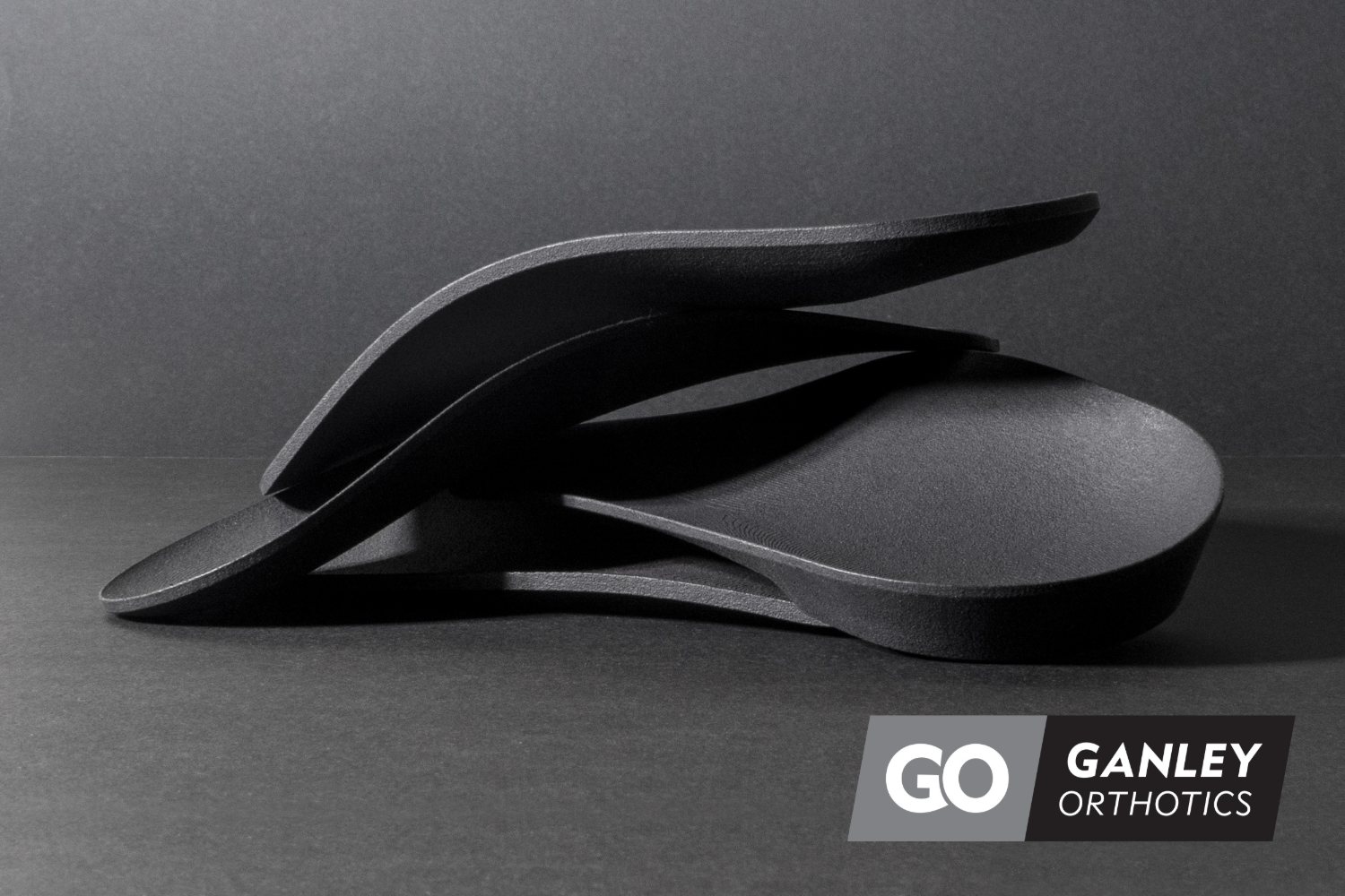 A set of precision-crafted Ganley Orthotics shells in a dark studio shot, showing their contoured shape