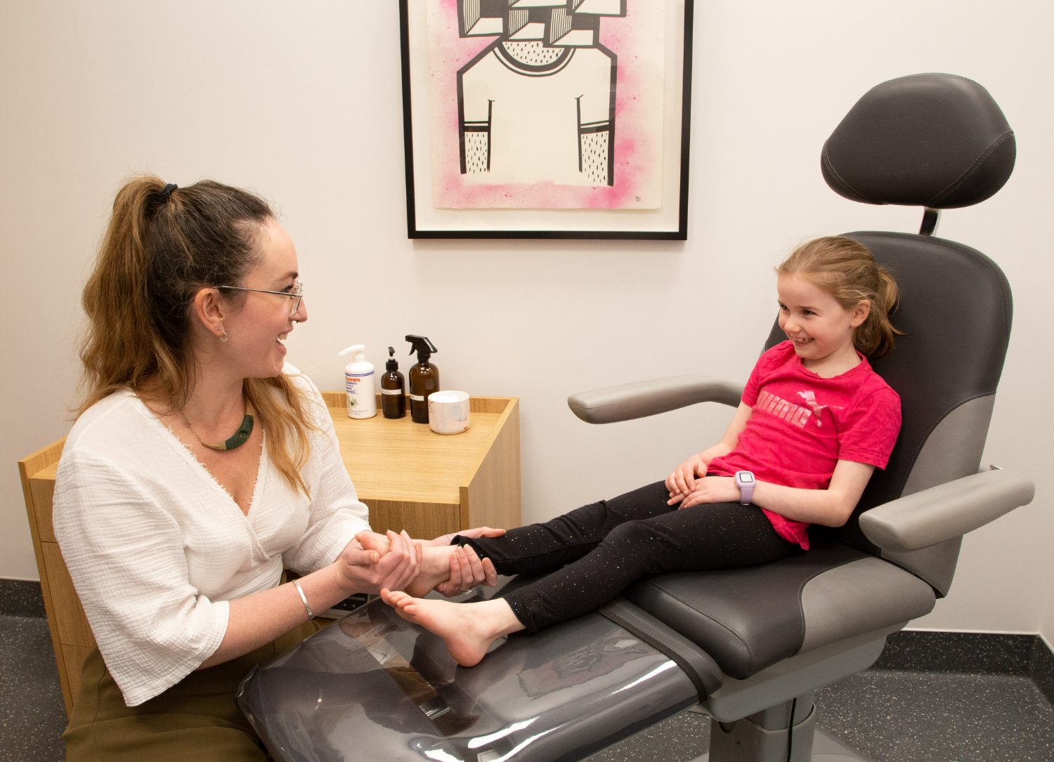 A podiatrist smiling with a young patient during a relaxed clinic visit